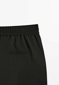 Svart elastisk midjebandbyxor med texturerad yta, försedd med en bakficka och detaljerad samlad midja.