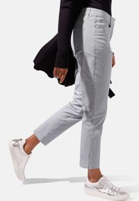Gestreepte, enkellange broek in lichtblauw en wit, met zijzakken en een middelhoog taille, gecombineerd met witte sneakers.