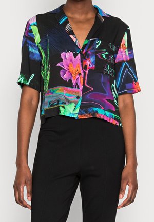 Koszula z krótkim rękawem na guziki z żywymi neonowymi kwiatowymi i abstrakcyjnymi wzorami, noszona wpuszczona do czarnych spodni z wysokim stanem.