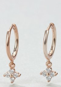 Orecchini a cerchio in oro rosa con un piccolo design floreale e quattro pietre trasparenti sospese dal cerchio. Finitura superficie liscia.