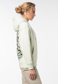 Lichtgroene hoodie met een voorzak, trekkoord en kleurrijke grafische patronen op de mouw. Zacht materiaal met een relaxed fit.