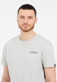Lichtgrijs katoenen T-shirt met een ronde hals, voorzien van een klein zwart "PROTEST" logo op de borst en een label op de mouw.
