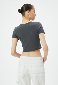 Grå kortærmet t-shirt med blød tekstur og rund halsudskæring, parret med højtaljede hvide cargo-bukser med store lommer.