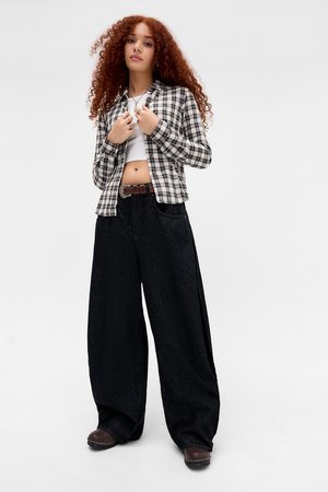 Black and white plaid button-up shirt, cropped, paired with loose dark denim wide-leg pants and brown clogs, with a visible brown belt.