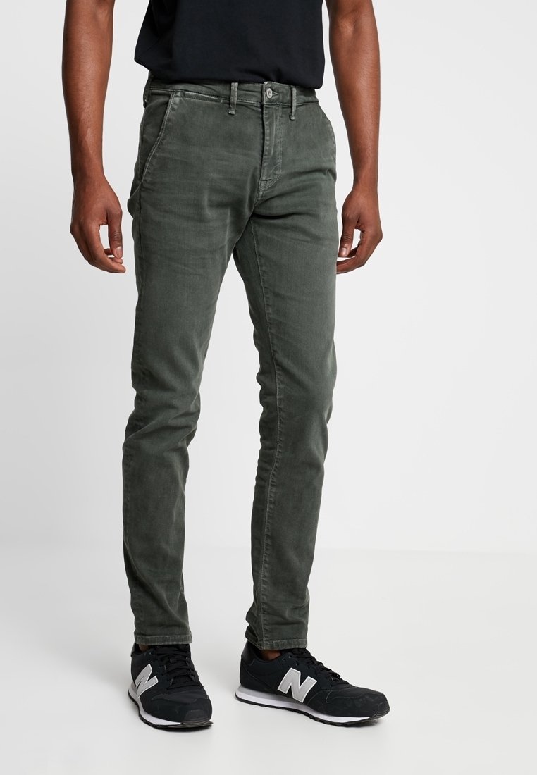 Zelené slim-fit kalhoty z měkkého strukturovaného materiálu. Mají zapínání na knoflík, boční kapsy a jemné švy. V sadě s černými teniskami.