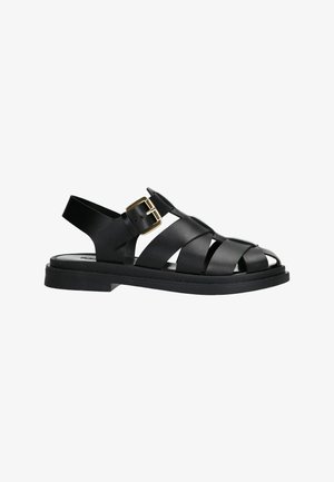 Black strappy sandals with a flat sole, featuring a buckle accent and open toe design. Made of smooth material and a textured insole.