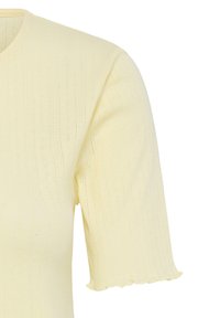 Haut en maille jaune pâle à manches courtes avec des motifs ajourés verticaux subtils et des ourlets de manches légèrement froncés.