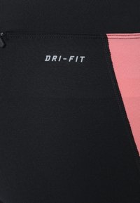 Black athletic fabric with pink accents; features "DRI-FIT" logo in white; smooth texture and streamlined shape with flat seams.