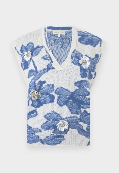 Gilet en tricot sans manches blanc avec des motifs floraux bleus et des épingles décoratives blanches et argentées en forme de fleurs à l'avant.