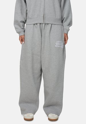 Szare spodnie dresowe wykonane z miękkiego materiału, z luźnym krojem, elastycznym pasem i białym logo na lewym udzie.