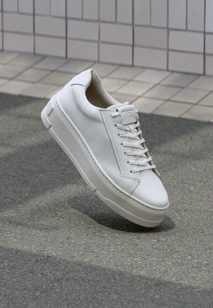 Witte leren sneaker met een glad oppervlak, afgeronde neus en minimalistisch ontwerp. Voorzien van platte veters en een dikke witte zool.