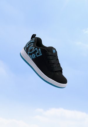 Czarny sneaker z niebieskimi geometrycznymi wzorami, grubą białą podeszwą i niebieskim bieżnikiem unoszący się na tle czystego nieba.