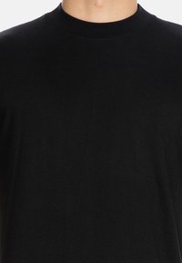 Czarny, krótki rękaw, bawełniany T-shirt. Posiada okrągły dekolt i gładką teksturę, bez widocznych wzorów czy zdobień.