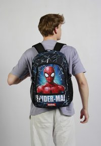 Sac à dos en tissu noir avec un grand motif Spider-Man au dos, des accents blancs et des poches latérales en mesh.