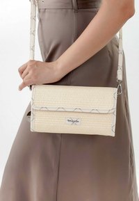 Borsa a tracolla intrecciata di colore crema con una forma strutturata, dotata di chiusura a patta, accessori in argento e una tracolla regolabile con un design stampato.