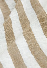 Tissu en lin présentant des rayures alternées marron et blanches. La texture est légèrement rugueuse avec un motif tissé, offrant un aspect naturel.