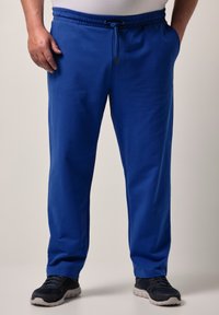 Blå sweatpants med dragsko i midjan, med sidfickor och ett mjukt, lätt tyg. Kombinerat med mörka sportskor.
