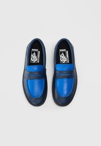 Modré a námořnické slip-on boty s hladkým koženým svrškem, mají zaoblenou špičku a kontrastní barevné bloky. Černá gumová podrážka.