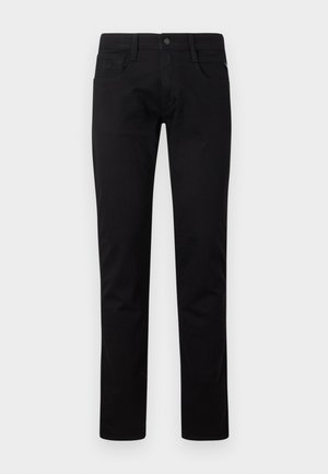 Črne ozke kavbojke z gumbom spredaj, zankami za pas in žepekmi na belem ozadju.