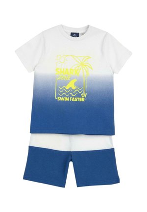 T-shirt a maniche corte con sfumatura bianca e blu, con grafica di uno squalo giallo, abbinata a pantaloncini blu con una striscia bianca all'orlo.