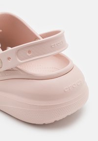 Sabot Crocs rose clair avec bride de talon réglable et détail de semelle texturée, montré en gros plan.