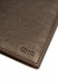 Brązowy skórzany portfel z fakturowaną powierzchnią i wytłoczonym logo "CHNK", z starannym przeszyciem wzdłuż krawędzi.