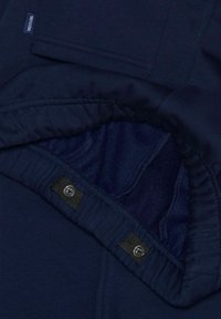Navyblauwe hoodie binnenkant met zachte fleece voering, verstelbare koord en knoopaccenten. Naaddetails zichtbaar langs de zoom.
