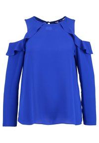 Blå blus med kallaxel-design, volangdetaljer på ärmarna och rund halsringning. Tillverkad av ett slätt, lätt tyg.