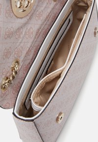 Lyserød mønstret håndtaske med guldfarvet hardware, der har flere indvendige rum og en glat beige foring.