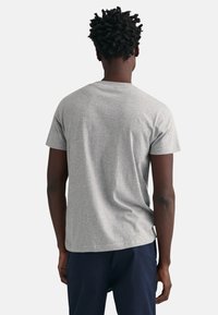 T-shirt gris à manches courtes avec un col arrondi, en tissu de coton, coupe décontractée, texture lisse et étiquette sur la couture latérale à l'ourlet.