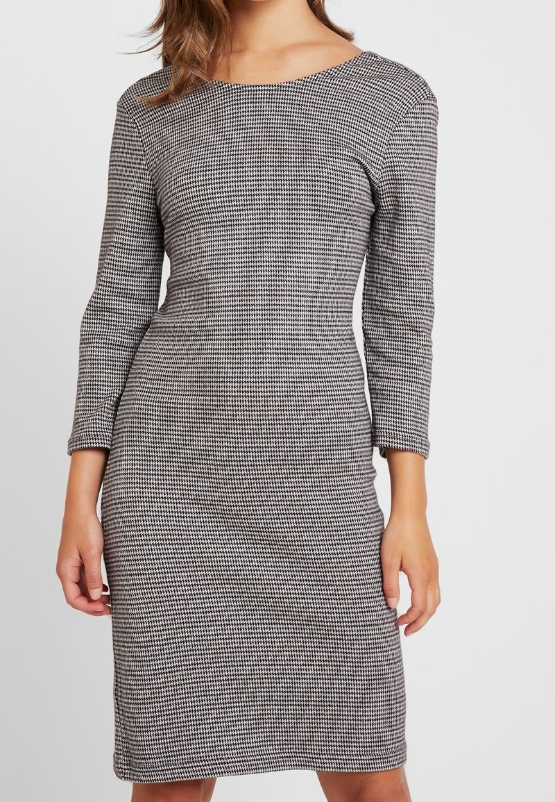 Klänning med hundtandsmönster, tillverkad av ett texturerat tyg, med båtformad halsringning och trekvartsärmar, skräddarsydd för en figurnära silhuett.