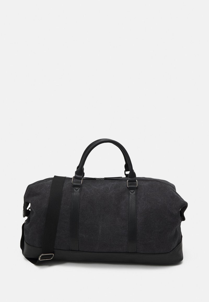 Sac de sport noir avec un dessus en tissu et un fond en simili cuir. Équipé de deux poignées et d'une bandoulière amovible. Fermeture éclair.