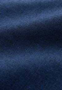 Gros plan d’un tissu texturé bleu foncé avec un motif tissé visible et de subtiles réflexions lumineuses mettant en valeur les plis du tissu.