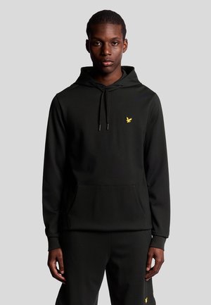 Sweatshirt à capuche noir avec une poche kangourou, arborant un petit logo d'aigle jaune sur la poitrine. Tissu doux et design décontracté.