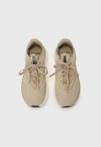 Baskets de sport beige avec une tige en tricot texturé, des lacets plats et une semelle intermédiaire blanche ; avec une semelle noire et un logo "SoftRide".