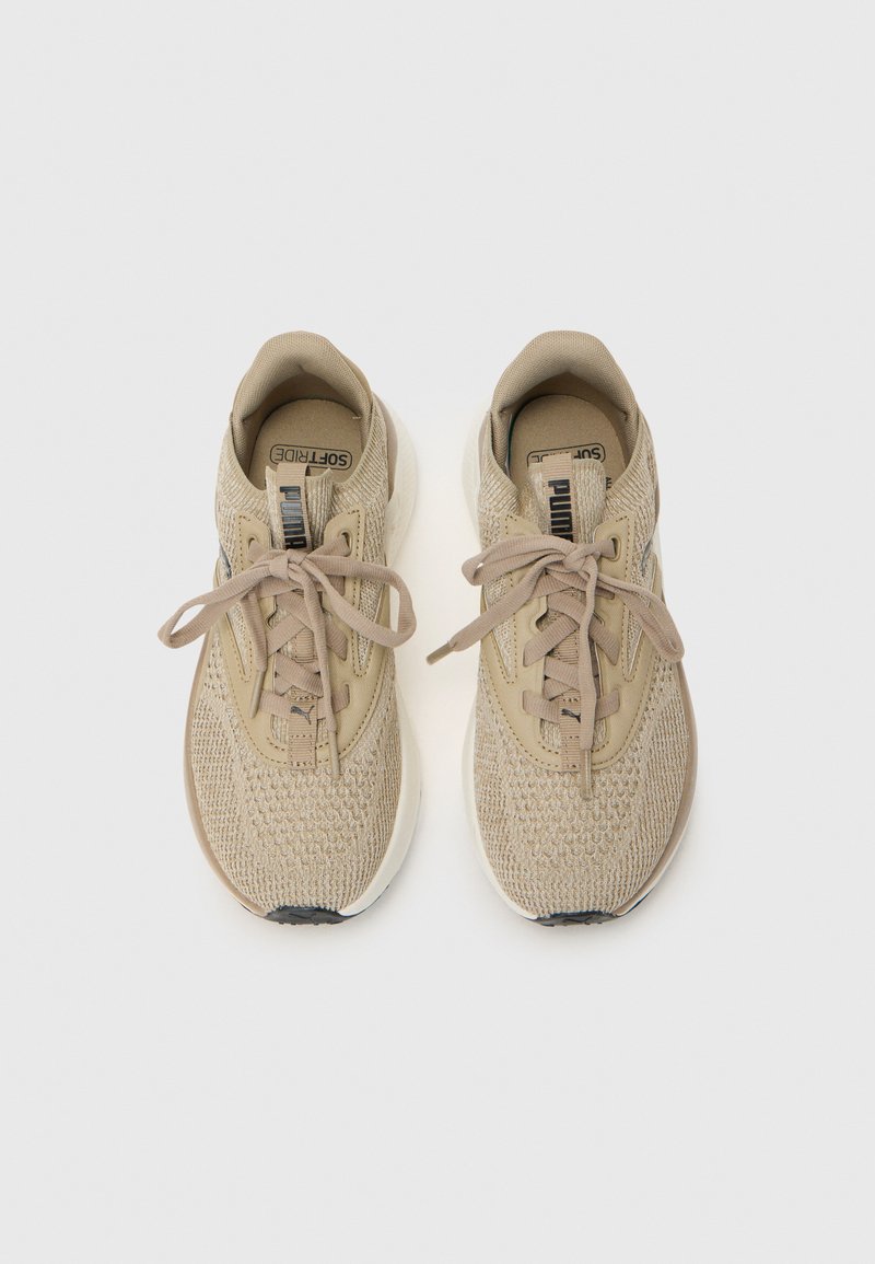 Zapatillas deportivas beige con un upper de tejido texturizado, cordones planos y una entresuela blanca; presentan una suela negra y la marca "SoftRide".