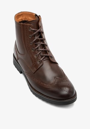 Brązowy skórzany botek za kostkę z wzorem brogue, sznurowadłami, zamkiem błyskawicznym i teksturowaną podeszwą. Gładkie wykończenie z precyzyjnymi perforacjami.