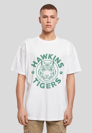 Weißes T-Shirt aus Baumwolle mit Rundhalsausschnitt, mit einem grünen Grafikdruck eines Tigerkopfs und dem Text "HAWKINS TIGERS" in fetten Buchstaben.