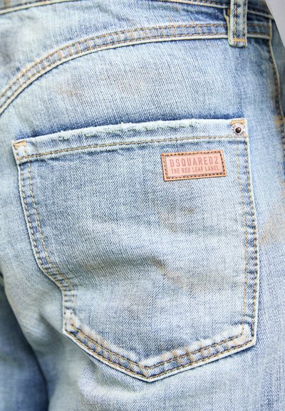 Jeans in denim azzurro con tasca posteriore e un piccolo etichetta in pelle rettangolare cucita sul lato superiore destro.