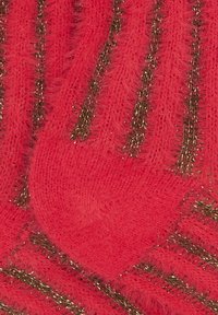 Calzini rossi pelosi con una texture morbida e strisce dorate metallizzate a contrasto. Il design ha un aspetto accogliente e caldo.