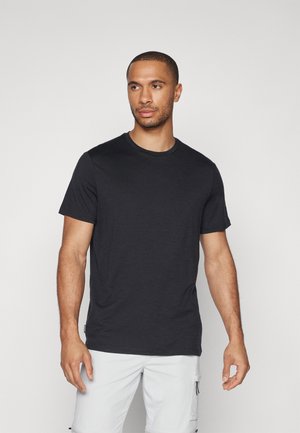 Svart kortermet t-skjorte laget av myk stoff, med klassisk rund hals, og en jevn tekstur, brukt med lyse cargo-shorts.