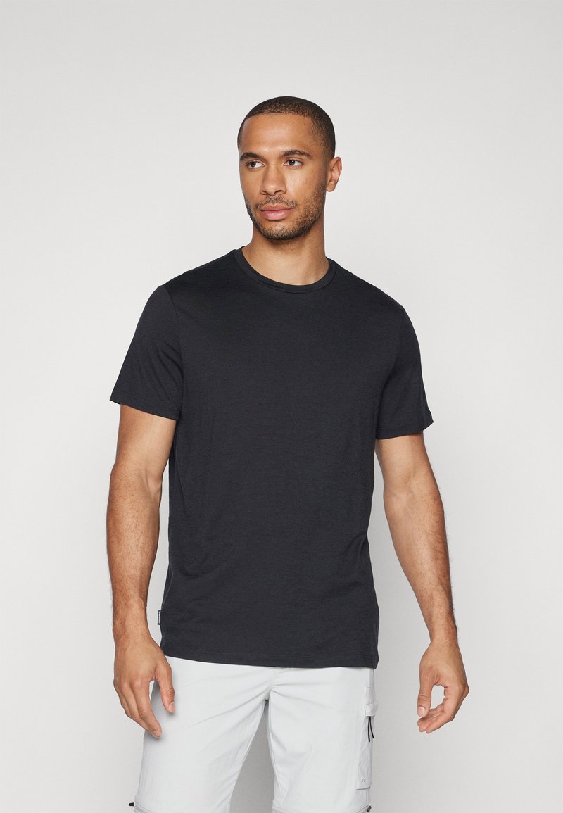Schwarzes T-Shirt mit kurzen Ärmeln aus weichem Material, mit klassischem Rundhalsausschnitt und glatter Textur, getragen mit hellen Cargo-Shorts.