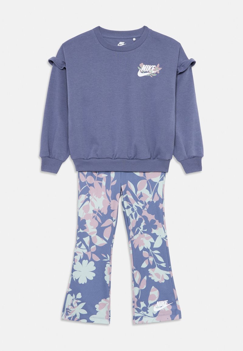 Dwuczęściowy strój dziecięcy Nike z lawendowymi spodniami w kwiatowy wzór i dopasowanym fioletowym sweatshirtem z logo Nike.