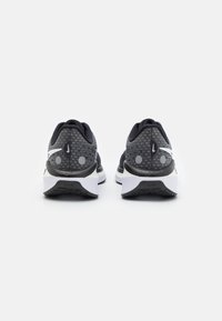 Baskets de sport noires et grises avec tige en mesh, accents blancs, semelle rembourrée et semelle extérieure texturée. Détails réfléchissants au niveau du talon.