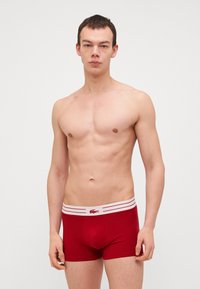 Rode katoenen boxershorts met een witte gestreepte tailleband met een logo. Het ontwerp is aangepast met een elastisch materiaal voor comfort.