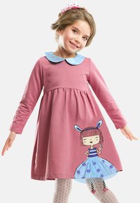 Vaaleanpunainen pitkähihaisen mekko, jossa on vaaleansiniset kaulukset ja sarjakuvatyttökuva; siinä on kerrottu hame ja pilkullisia sinisiä yksityiskohtia.