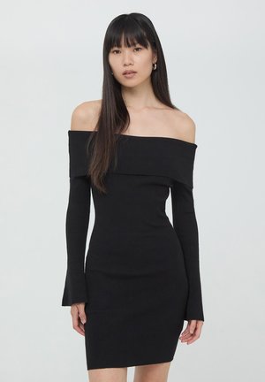 Abito nero a coste con scollo off-the-shoulder, maniche lunghe, silhouette aderente e lunghezza sotto il ginocchio. Tessuto elasticizzato con una superficie liscia.