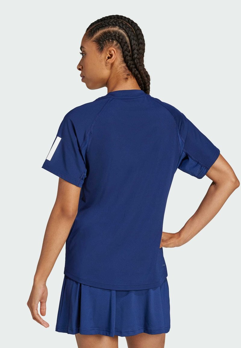 Camiseta atlética azul marino de manga corta y diseño raglán, combinada con una falda plisada a juego. Textura suave, con un branding mínimo.