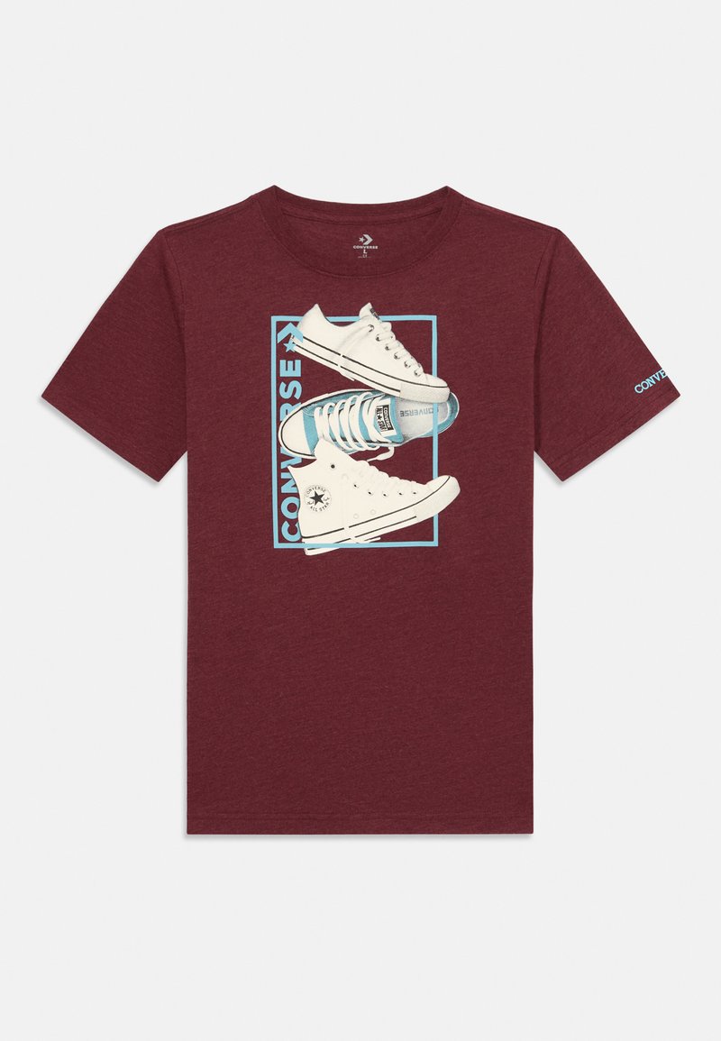 Bordové tričko s krátkým rukávem, na kterém je grafika bílých tenisek Converse s modrými akcenty a text "CONVERSE" v obdélníkovém rámečku.