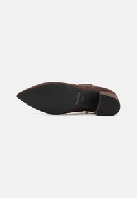 Brown suede high-heeled shoe with pointed toe and a textured black rubber sole. Stitched detail along the vamp and heel. Brand name visible.